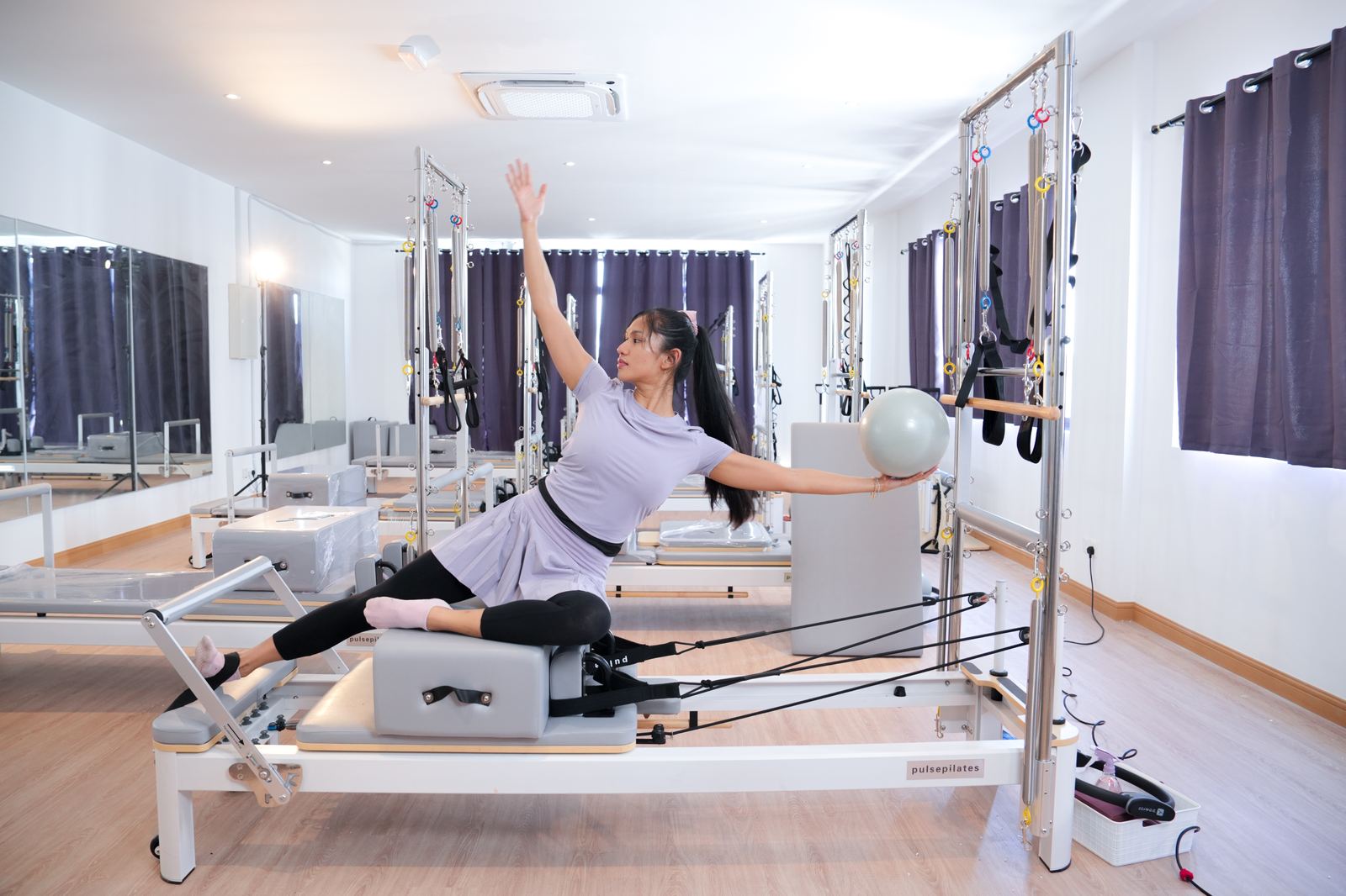 Ninlates instructor reaching through a reformer stretch in the studio